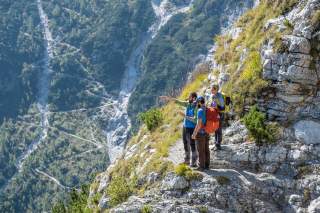 Eine dreiköpfige Wandergruppe orientiert sich mittels Smartphone im Gebirge.