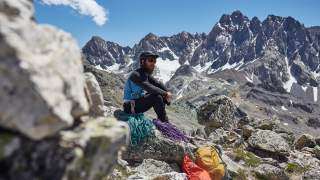 Mann sitzt mit Kletter-Equipment in den Bergen