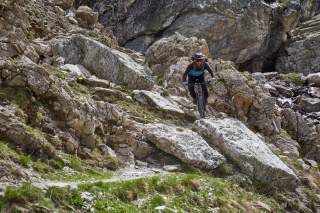 Mann auf Mountainbike fährt blockigen Trail runter