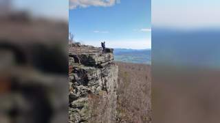 Eine Frau auf dem flachen Felsvorsprung des Hohen Schneebergs.