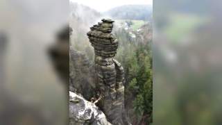 Ein rieser Felsturm ragt in die Höhe, im Hintergrund sieht man ganz winzig die nächsten Häuser.