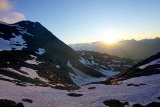 Untergehende Sonne in den Bergen, Schneefelder im Vordergrund