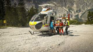 Bergretter verfrachten eine Trage mit einem Verunfallten in einen Rettungshubschrauber.