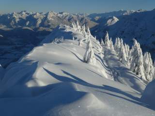Verschneite Alpenlandschaft, aufgenommen von einer Bergspitze.