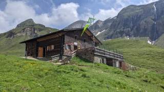 Hütte mit Fahne vor Gebirgskulisse