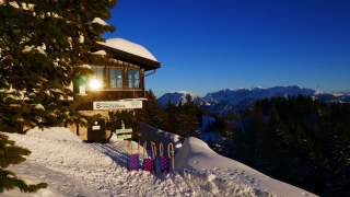 Brünnsteinhaus im Winter mit Rodel und Blick ins Kaisergebirge