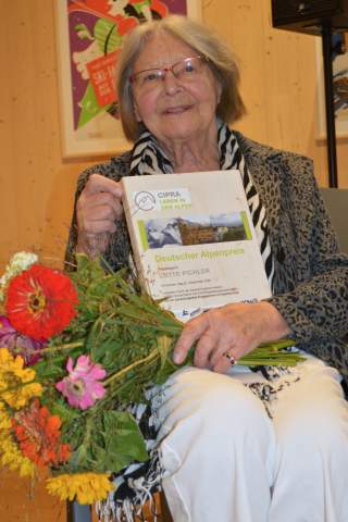 Lotte Pichler zeigt die Urkunde des Deutschen Alpenpreis.