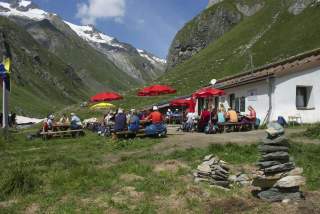 Hütte mit Terrasse und roten Sonnenschirmen in Berglandschaft