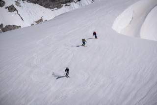 Drei Personen fahren auf Ski Hang hinunter