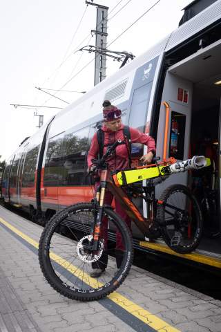 Frau steigt mit Fahrrad und Ski aus Zug aus