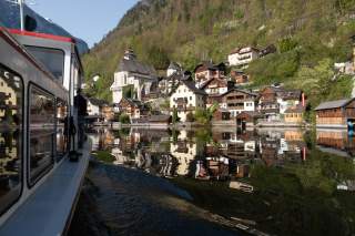 Boot fährt über See auf an Berghang gelegenes Dorf zu