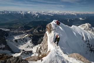 Personen klettern auf schneebedecktem Gipfelgrat