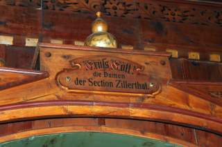 Holzschild mit der Gravur „Grüß Gott! die Damen der Section Zillerthal.“ oberhalb eines hölzernen Bogens in traditionellem Stil.