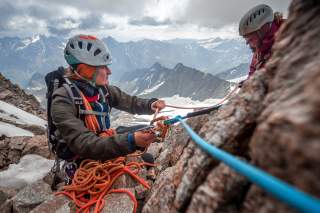 2 Frauen mit Hochtourenausrüstung angeseilt am Fels, im Hintergrund Bergpanorama