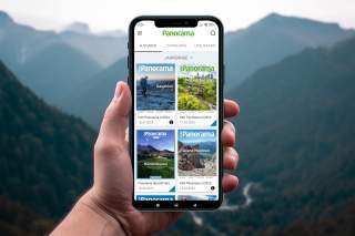 Smartphone mit DAV Panorama App vor Bergkulisse
