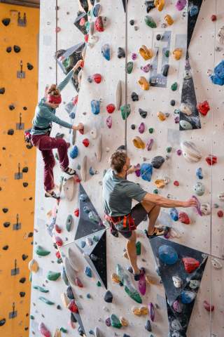 Zwei Menschen klettern in Kletterhalle mit Selbstsicherung