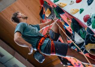 Sportler greift während des Kletterns in seinen Chalkbag