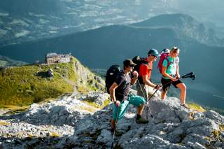 Drei Menschen stehen in Felsen oberhalb von Berghütte