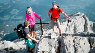 Drei Menschen stehen auf Berg an Gipfelkreuz