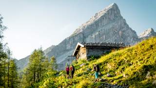 Drei Menschen wandern durch Almgelände auf Watzmann zu