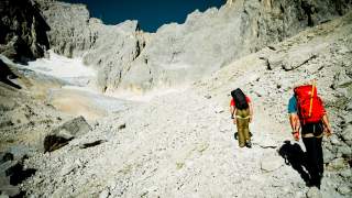 Zwei Menschen wandern durch Moränenlandschaft Richtung Gletscher