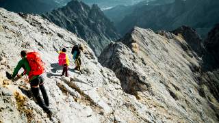 Drei Bergsteigende an felsigem Grat