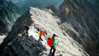 Drei Bergsteigende auf Berggrat