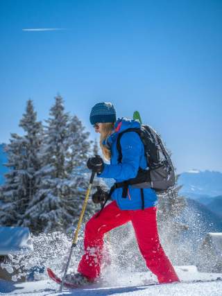 Frau geht auf Schneeschuhen durch tiefen Schnee