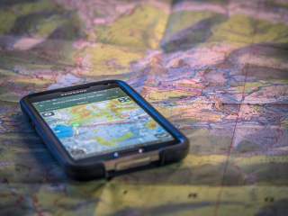 Smartphone mit Tourenapp auf analoger Landkarte