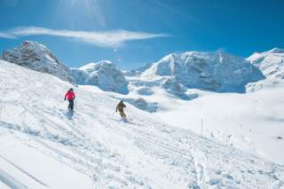 Zwei Personen fahren mit Ski auf Gletscher ab