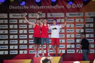 Drei Athleten halten ihre Pokale bei der Siegerehrung.