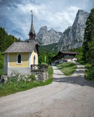 Kapelle und Weg zu Berghütte vor Felswänden