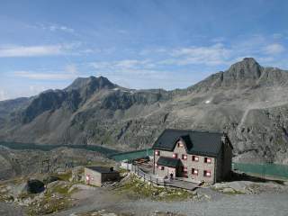 Hütte vor türkisem See in Bergwelt