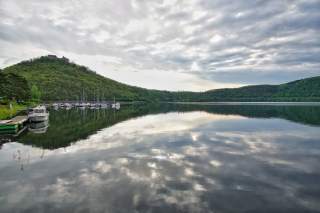 Im Edersee spiegelt sich der wolkige Himmel, Seegelboote am Steg