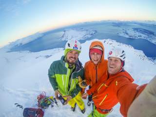 Drei Männer ins Eiskletterausrüstung machen ein Selfie. Im Hintergrund sieht man Schnee, Eis und das Meer. Drei Männer ins Eiskletterausrüstung machen ein Selfie. Im Hintergrund sieht man Schnee, Eis und das Meer.