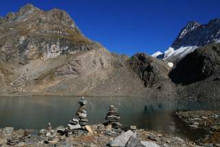 Bergsee im Hochgebirge, ein Gipfel im Hintergrund ist mit Schnee gezuckert