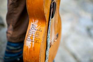 Nahaufnahme einer alten Gitarre mit handschriftlichem Text an der Seite.