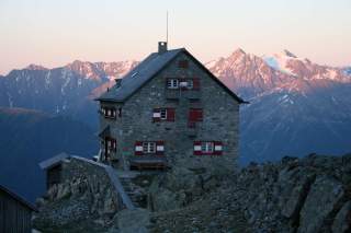 Hütte im Abendrot vor Gipfeln