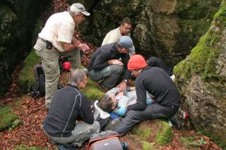 Fünf Menschen leisten Erste Hilfe am Fels.