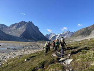 Gruppe von Frauen mit Rucksäcken läuft durch Landschaft Grönlands