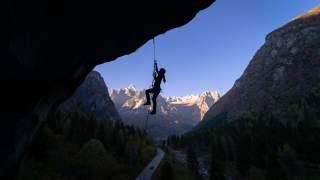 Frau im Schatten am Seil vor Bergkette, die von der Sonne angestrahlt wird