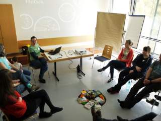 Menschen sitzen im Stuhlkreis in Raum