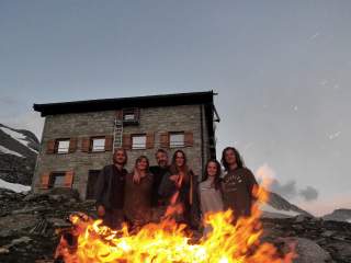 Familie an Lagerfeuer vor Berghütte