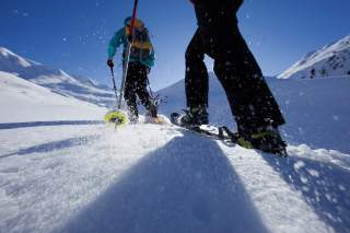 Zwei Menschen laufen auf Schneeschuhen durch winterliche Berglandschaft