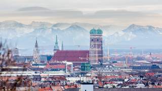 Scheinbar ganz nah hinter München erheben sich die Alpen. Dominant in der Bildmitte: die Frauenkirche mit ihren zwei Türmen.