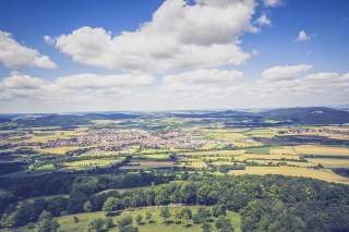 Luftbild der Fränkischen Alb mit sommergelben Feldern unter großen Wolken.