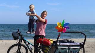 Astrid hält Nelion in die Luft, im Hintergrund das Meer. Sie war mit dem Fahrrad unterwegs.