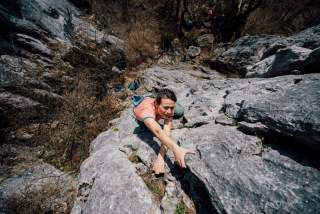 Am Fels kletternde Frau von oben gesehen