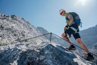 Bergsteiger mit Helm und Klettersteigset gesichert am Drahtseil