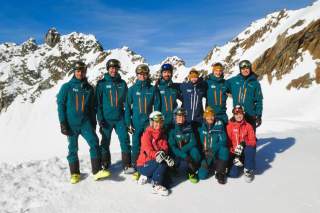 Gruppenfoto des Lehrteams Skilauf im Schnee mit Berggipfeln im Hintergrund